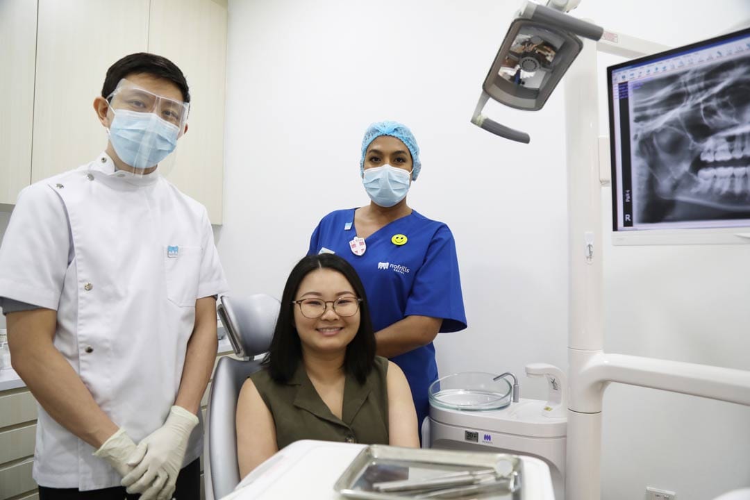Dr-Joshua-Chong-with-patien-in-nofrills-dental-at-suntec-city dentists and patient posing together