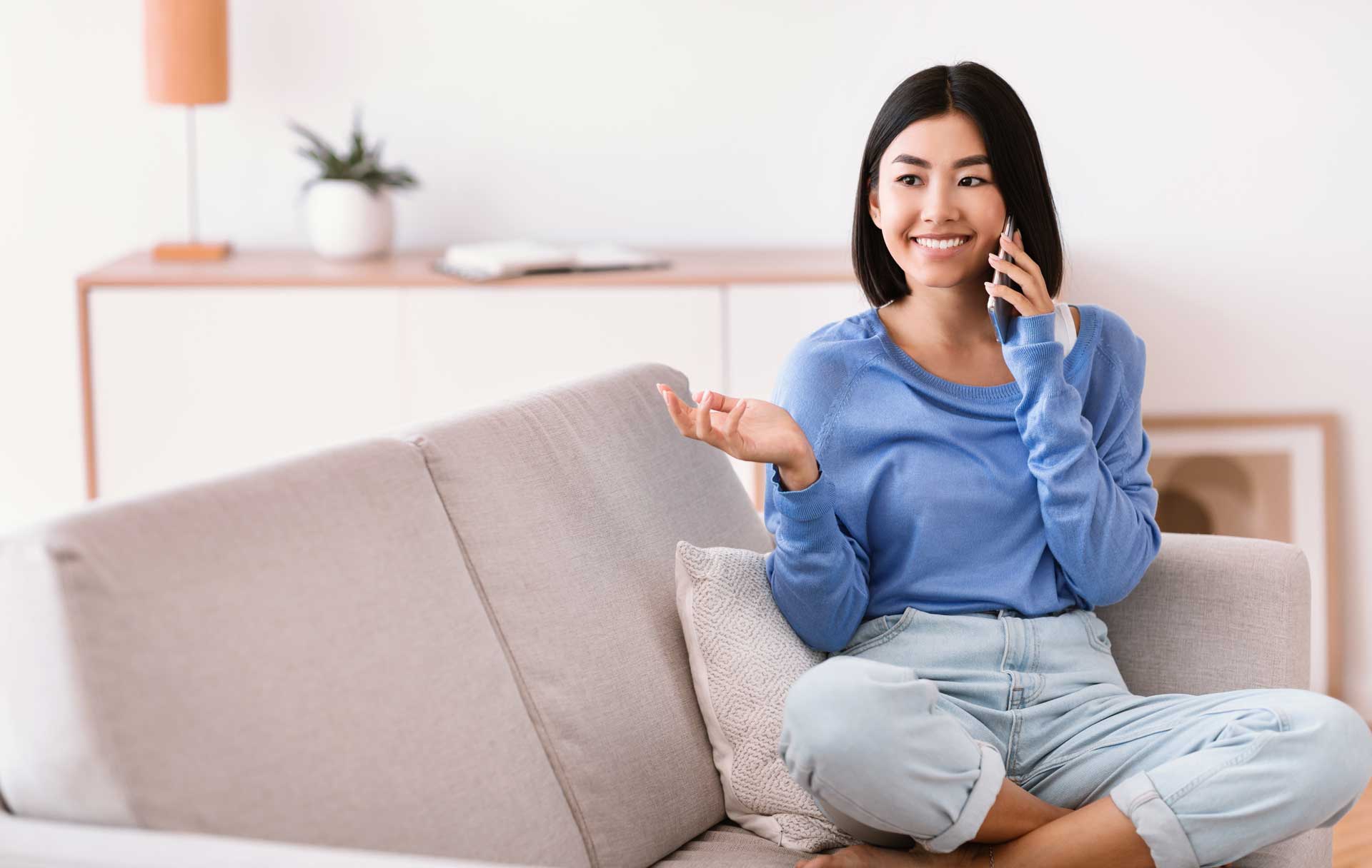 smiling-asian-woman-talking-on-mobile-phone-sittin-SNWACZS Happy asian woman smiling with her dental veneers years after getting dental veneer treatment