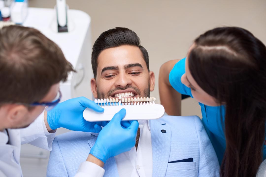 young-man-visiting-dentist-2X4M98G young man getting his teeth checked for the right tooth shade before getting dental veneers
