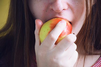 woman biting on apple