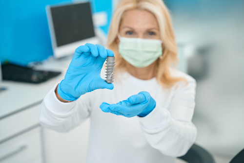 dentist holding dental implant